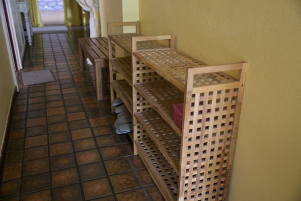 Le couloir carrelé de l'entrée et ses étagères à chaussures en bois