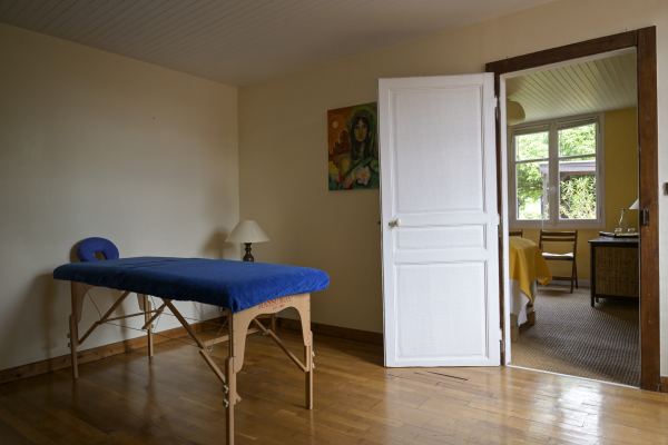 Une table de massage bleue devant la porte ouverte sur la seconde salle